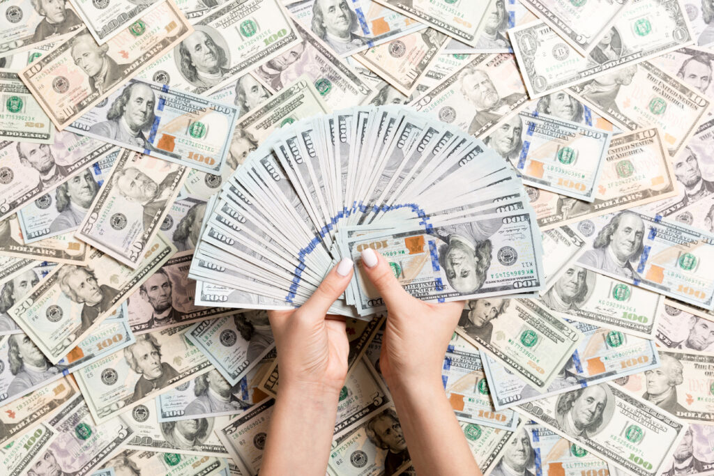 top view of female hands counting money on different dollar background. debt concept. investment concept